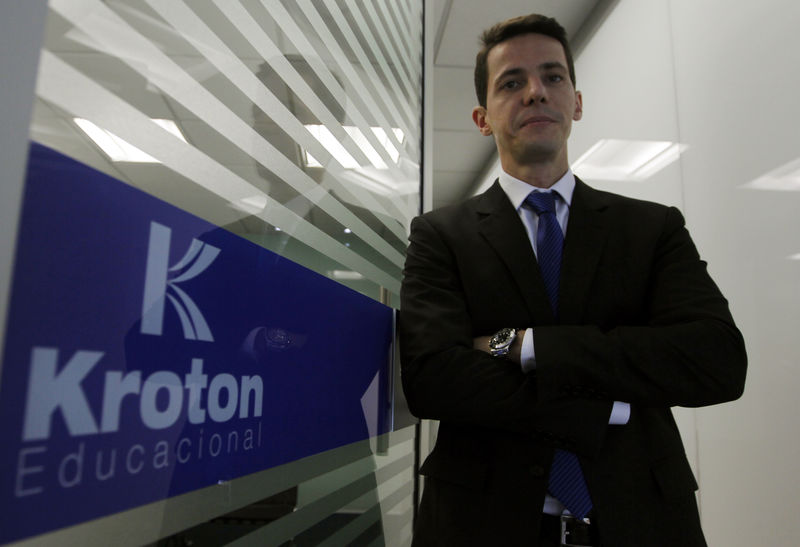 © Reuters. CEO da Kroton, Rodrigo Galindo ao lado de logo da empresa