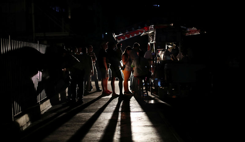© Reuters. Personas reunidas cerca de un carrito de comida durante un apagón en Caracas