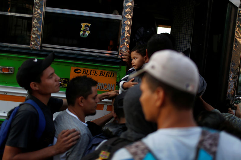 © Reuters. People board a bus in a caravan of migrants en route to U.S. in San Salvador