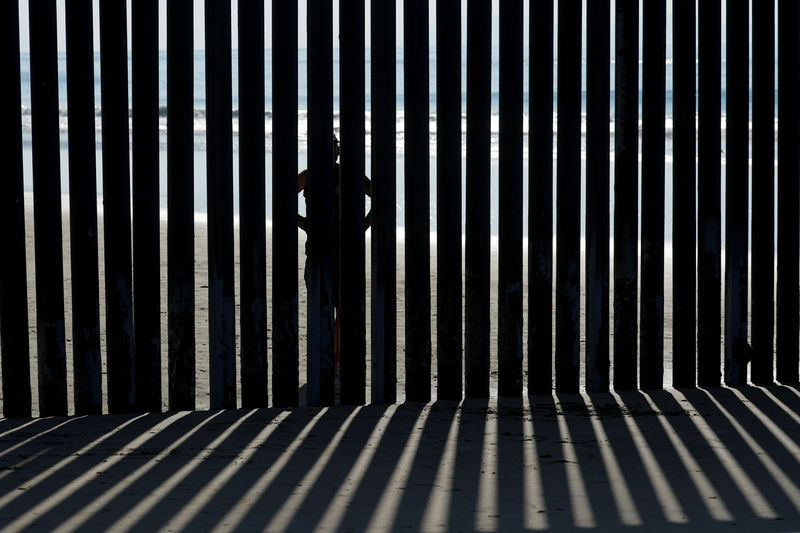 © Reuters. FILE PHOTO: A person looks through the border wall towards the United States at Border Field State Park in San Diego