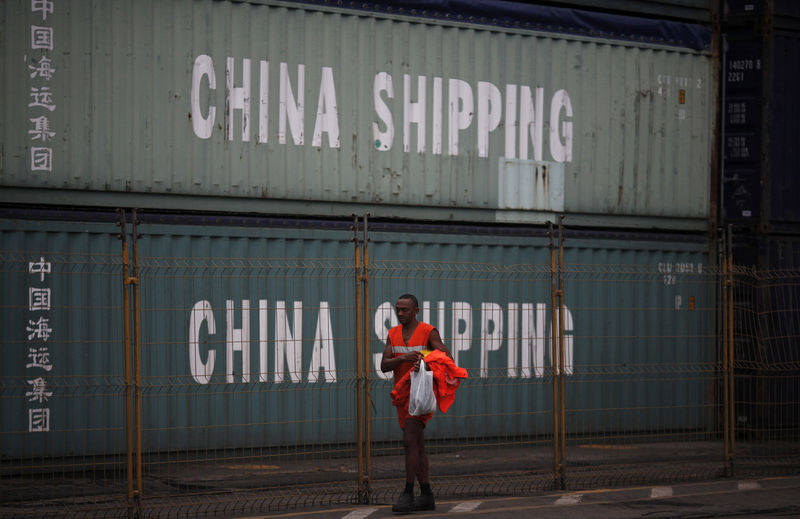 © Reuters. FILE PHOTO: Worker walks past by containers from China Shipping company at Brazil's main ocean port of Santos city