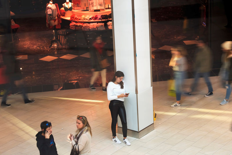 © Reuters. A woman leans against a column using her smartphone outside a Victoria's Secret at the King of Prussia Mall, United States' largest retail shopping space, in King of Prussia