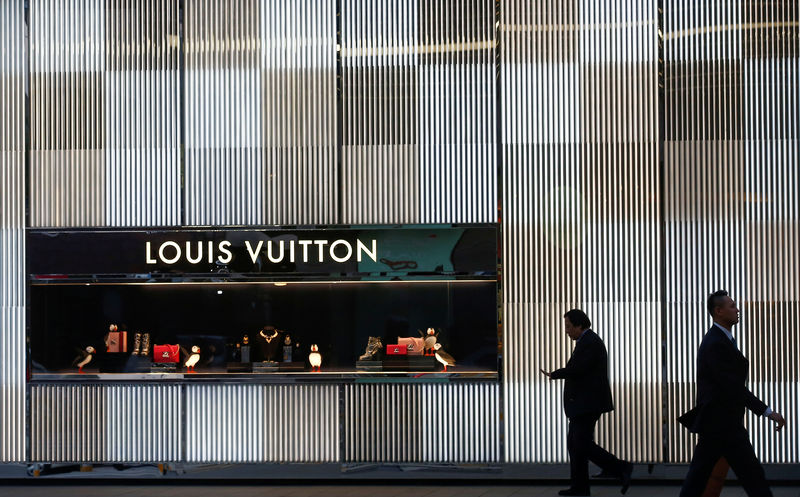 © Reuters. FILE PHOTO: Men walk past a boutique of the Louis Vuitton luxury goods company in Beijing