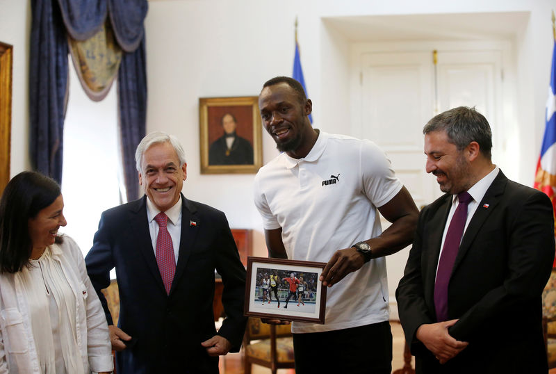© Reuters. El medallista olímpico Usain Bolt posa junto al presidente chileno, Sebastián Piñera, mostrando un fotomontaje que le obsequió el mandatario durante una visita a Santiago