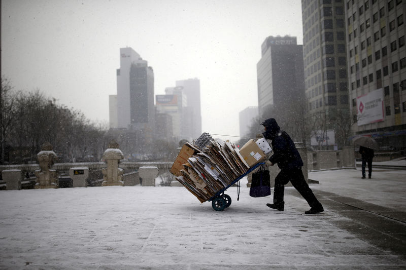 © Reuters. FILE PHOTO: A man carries scraps in a handcart during snowfall in central Seoul