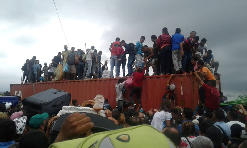 © Reuters. Gente sube a un contenedor utilizado como barricada en el puente fronterizo internacional Simón Bolívar en San Antonio del Táchira, Venezuela.