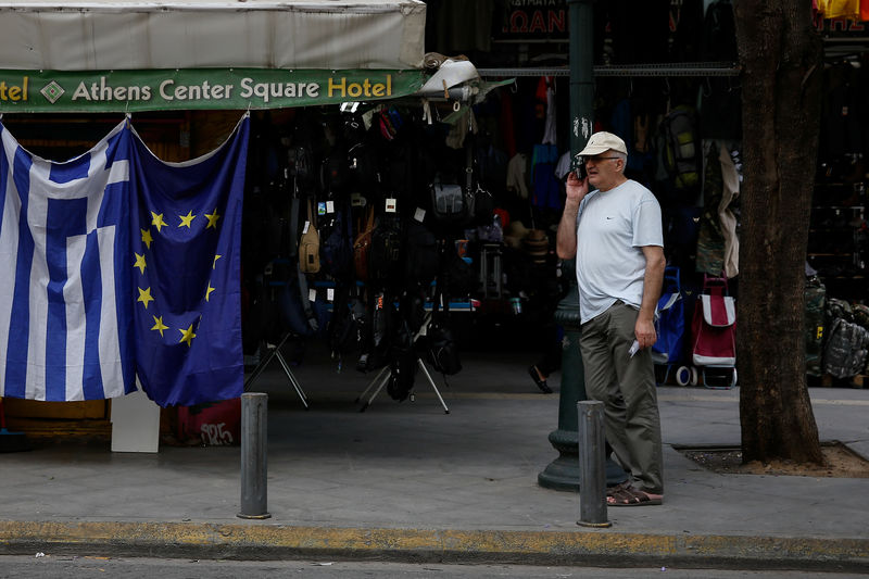 © Reuters. FILE PHOTO: A man stands next to a kiosk selling Greek and EU flags in Athens