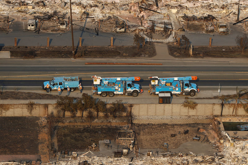 © Reuters. FILE PHOTO: Pacific Gas and Electric (PG&E) trucks are seen parked on a road between homes destroyed by the Tubbs Fire in Santa Rosa, California