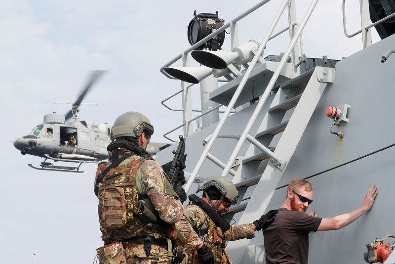 © Reuters. FILE PHOTO: Italian marines check a crew member as they patrol the British Royal navy vessel Echo, during the NATO Operation Sea Guardian in Mediterranean sea, off the coast of Taranto