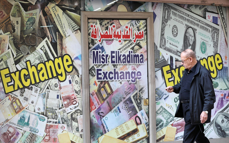 © Reuters. FILE PHOTO: A man walks past a currency exchange bureau advertisement showing images of the U.S. dollar and other currencies in Cairo