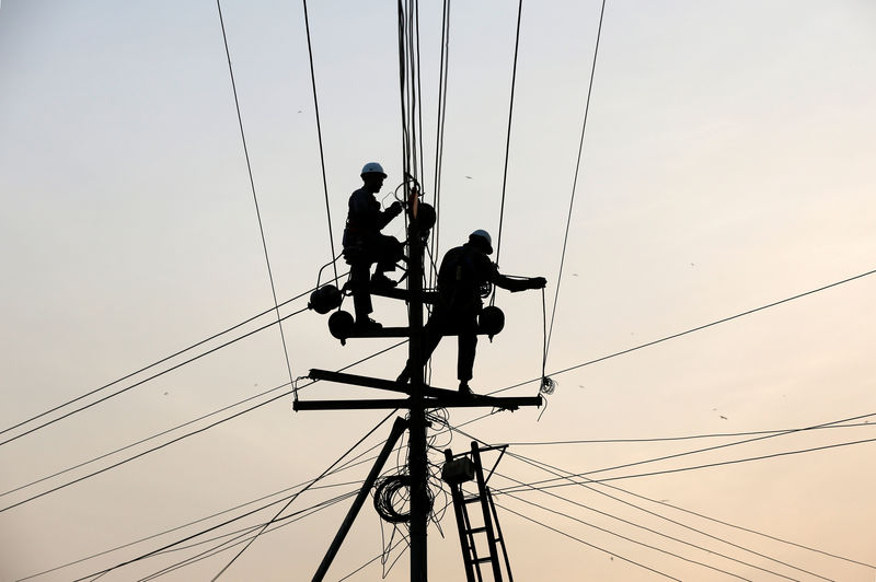 © Reuters. Trabalhadores realizam manutenção de fiação elétrica