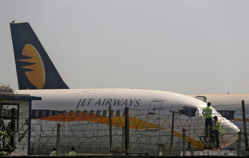 © Reuters. FILE PHOTO: Workers cover the cockpit window of a Jet Airways aircraft parked at the Chhatrapati Shivaji Maharaj International Airport in Mumbai