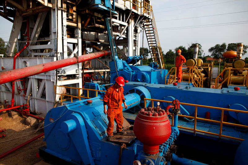 © Reuters. FILE PHOTO: Men work on an oil rig at Sinopec's Shengli oil field in Dongying