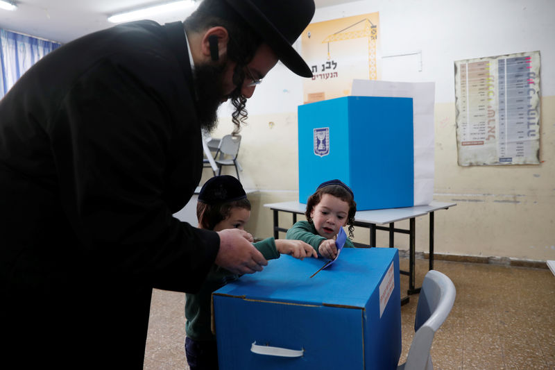 © Reuters. Un judío ultraortodoxo ayuda a los niños a depositar su voto en una mesa electoral en Jerusalén