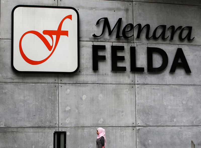 © Reuters. FILE PHOTO:  A woman walks past a logo of Felda in Kuala Lumpur