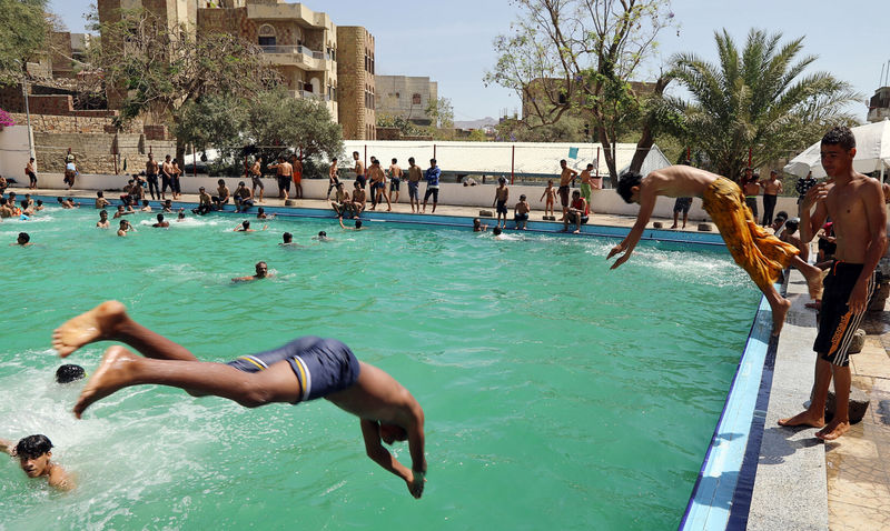 © Reuters. Boys jump into a swimming pool in Taiz