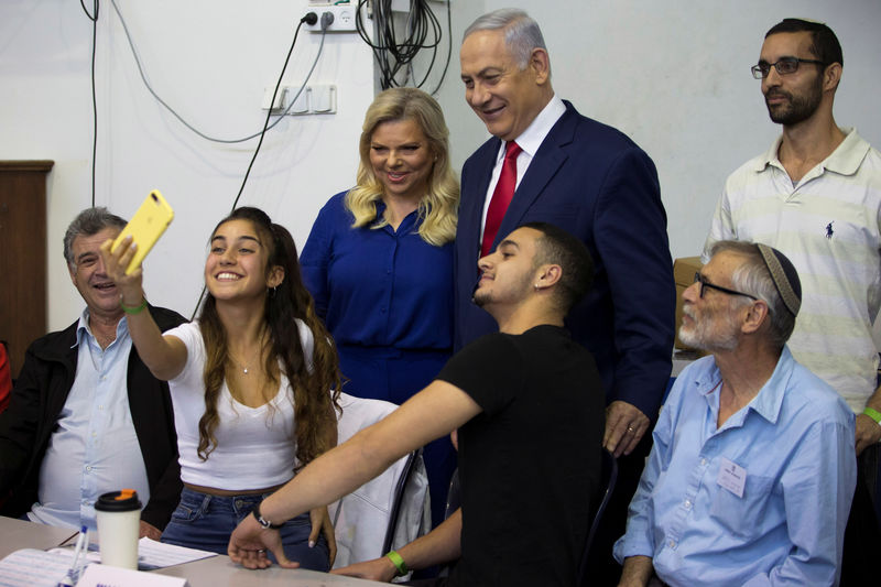 © Reuters. A youth takes a selfie with Israel's Prime Minister Benjamin Netanyahu and his wife Sara after they voted in Israel's parliamentary election in Jerusalem