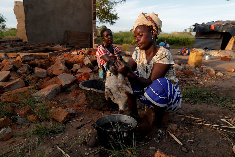 © Reuters. Maria Jofresse, de 25 años, observa a su madre Ester Thoma preparar la comida junto a su casa dañada después del ciclón Idai, en el pueblo de Cheia