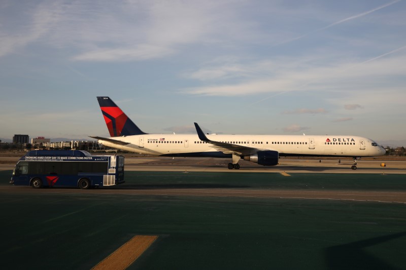 © Reuters. FILE PHOTO:  A Delta plane passes a Delta bus on the tarmac at LAX airport in Los Angeles