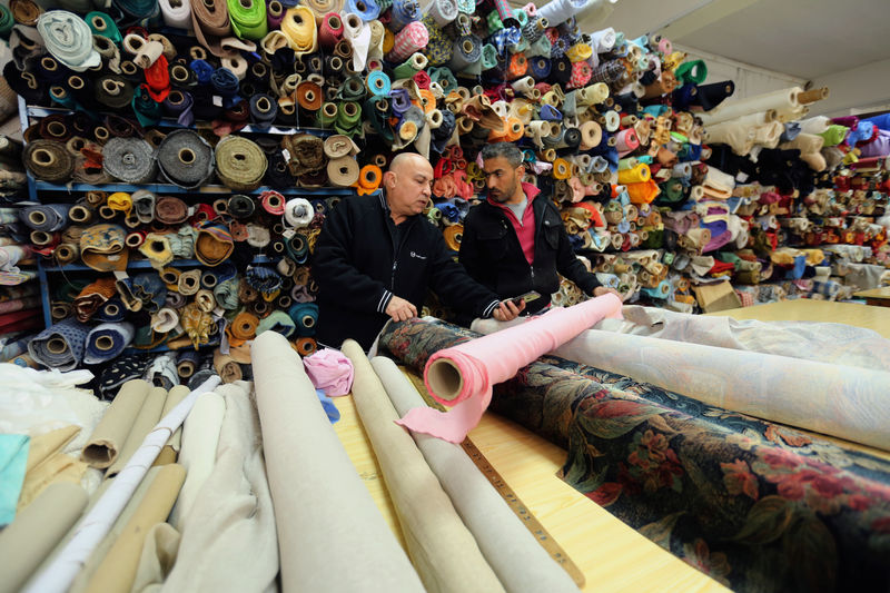 © Reuters. Men check fabric inside the Mzannar family's textile shop, in Baabda