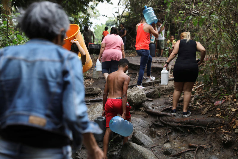 © Reuters. Pessoas carregam garrafas e galões para encherem de água em um rio de Caracas, na Venezuela