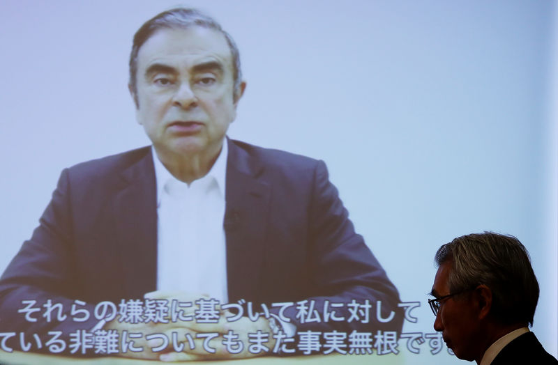 © Reuters. Junichiro Hironaka, chief lawyer of the former Nissan Motor chairman Carlos Ghosn, walks in front of a screen showing Ghosn's video statement during a news conference at Foreign Correspondents' Club of Japan in Tokyo