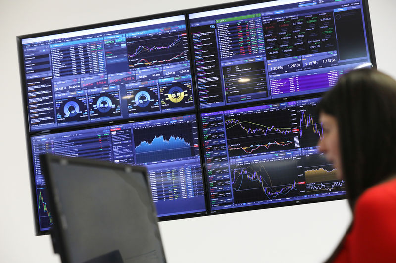 © Reuters. A trader works as a screen shows market data behind her at CMC markets in London