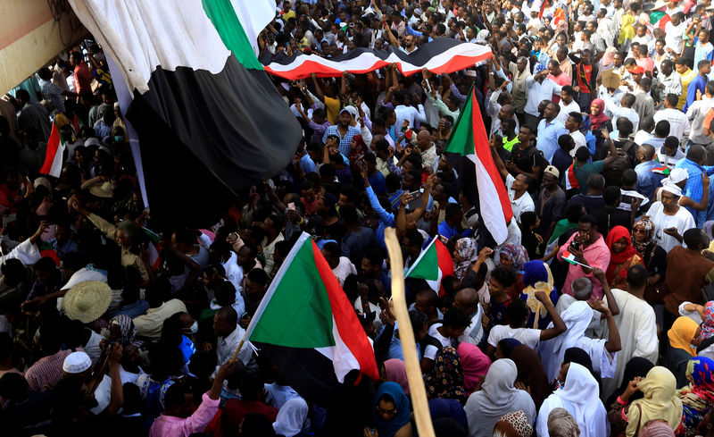 © Reuters. Sudanese demonstrators wave their national flag as they attend a protest rally demanding Sudanese President Omar Al-Bashir to step down outside the Defence Ministry in Khartoum