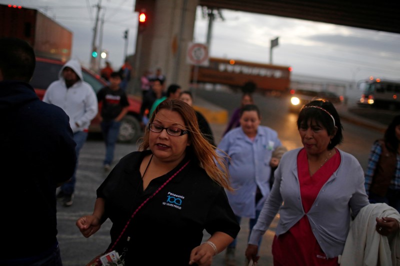 © Reuters. FILE PHOTO: Workers of assembly factories cross a street as they rush toward their shift at an industrial park in Reynosa