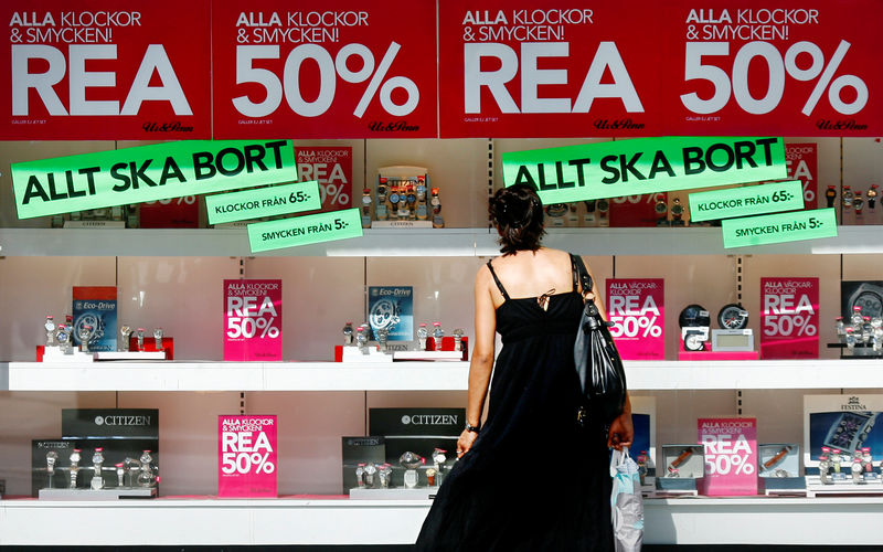 © Reuters. Woman looks in window of shop advertising sale in downtown Stockholm