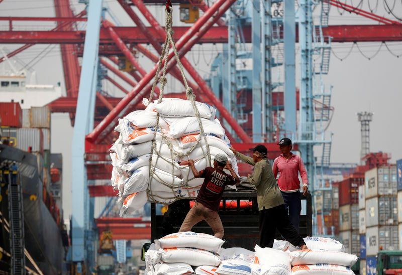 © Reuters. FILE PHOTO: Workers help unload bags of rice from a cargo ship onto a truck at Tanjung Priok Port in Jakarta,