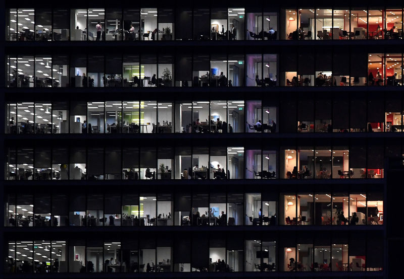 © Reuters. FILE PHOTO: Workers are seen in an office tower in the Canary Wharf financial district at dusk in London