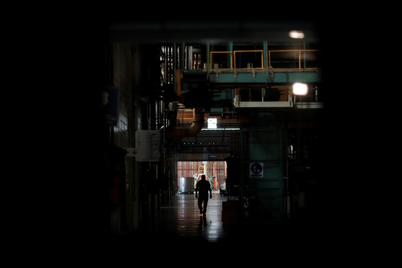 © Reuters. Un trabajador camina junto a maquinarias detenidas en una factoría urante un apagón en Valencia, Venezuela.