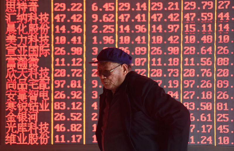© Reuters. Homem caminha em frente a painel eletrônico de ações em Hangzhou, China