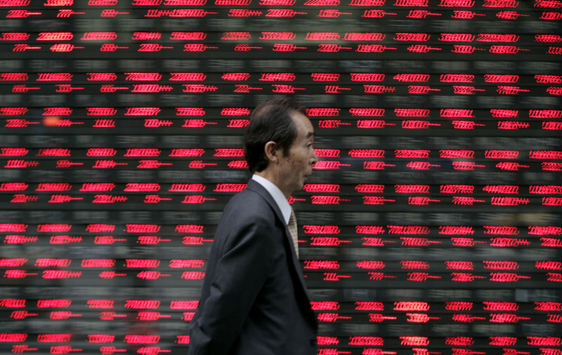 © Reuters. A pedestrian walks past a stock price display at a brokerage in downtown Tokyo
