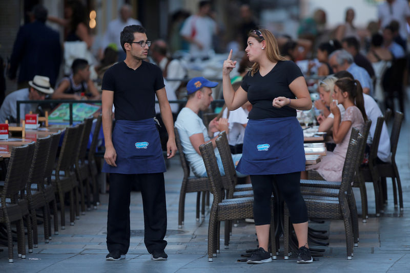 © Reuters. FILE PHOTO: A waitress and a waiter chat as they wait for customers at the terrace of a restaurant in downtown Ronda