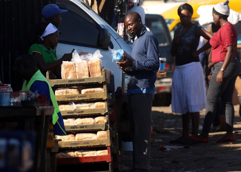 © Reuters. A man buys bread from a street vendor in Mbare township