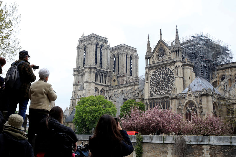 © Reuters. Transeúntes toman fotografías de la catedral de Notre-Dame en París después del incendio que destruyó partes de la estructura gótica.  April 16, 2019.   REUTERS/Gonzalo Fuentes