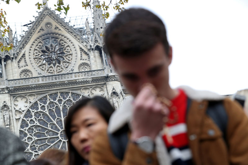 © Reuters. People pray near Notre-Dame Cathedral after a massive fire devastated large parts of the gothic structure in Paris