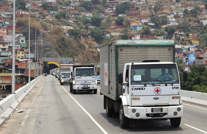 © Reuters. Camiones de la Cruz Roja y la Media Luna Roja con ayuda humanitaria circulan por una autopista de Caracas.