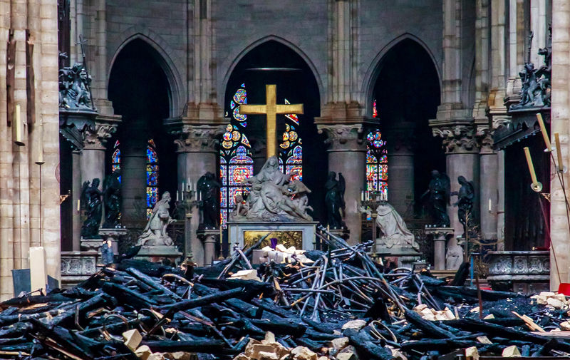 © Reuters. La cruz y la escultura de la Piedad de Nicolas Coustou en el fondo de los escombros del interior de Notre-Dame de Paris, después del incendio que devastó la catedral, durante la visita del Ministro del Interior francés, Christophe Castaner, en París.