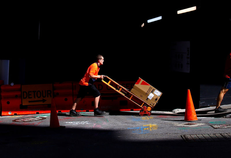 © Reuters. FILE PHOTO: A worker pushes a trolley loaded with goods past a construction site in the central business district of Sydney
