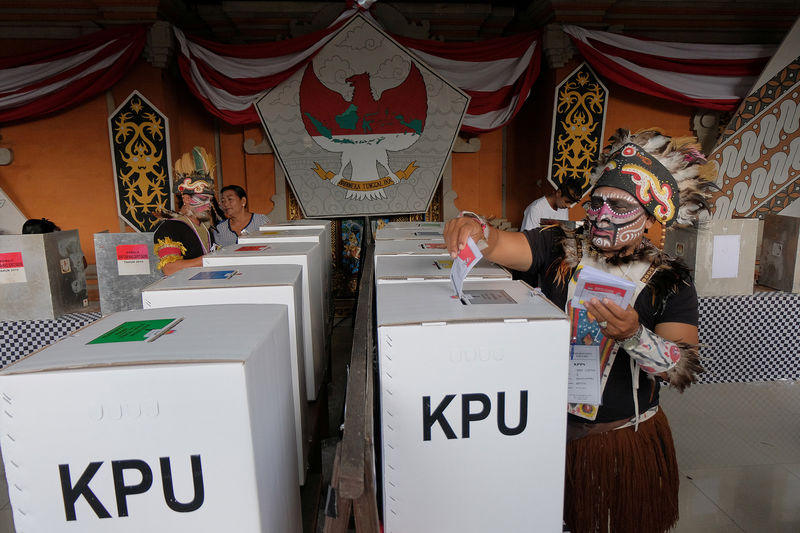 © Reuters. Electoral officials wear Indonesian traditional costumes from Papua during elections at a polling center in Badung