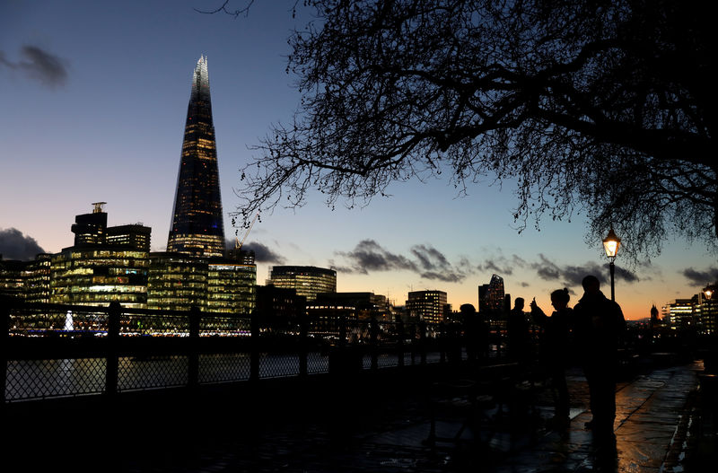 © Reuters. FILE PHOTO: People walk alongside the Thames as the sun sets behind The Shard in London
