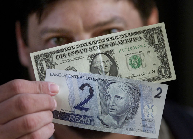 © Reuters. Homem segura notas de 1 dólar e 2 reais