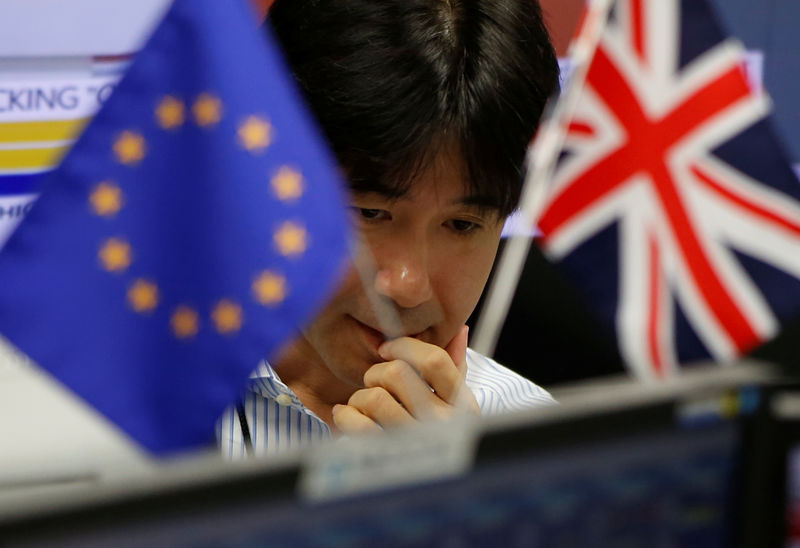 © Reuters. An employees of a foreign exchange trading company works as he is seen between British Union flag and an EU flag in Tokyo