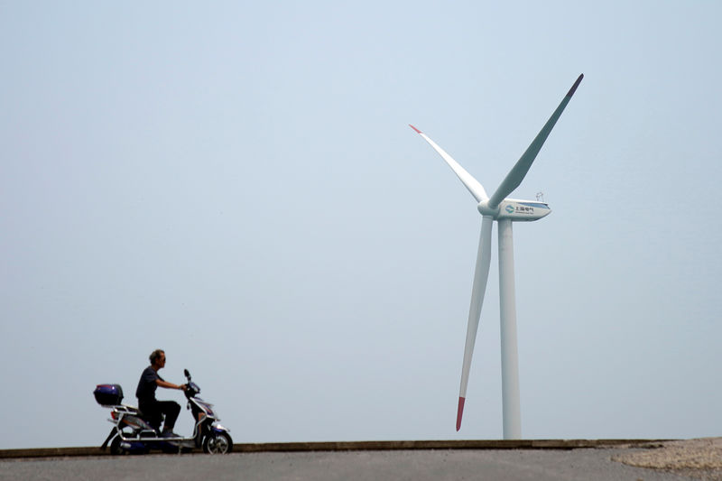 © Reuters. FILE PHOTO:  A man rides an electric scooter past a wind turbine in Shanghai
