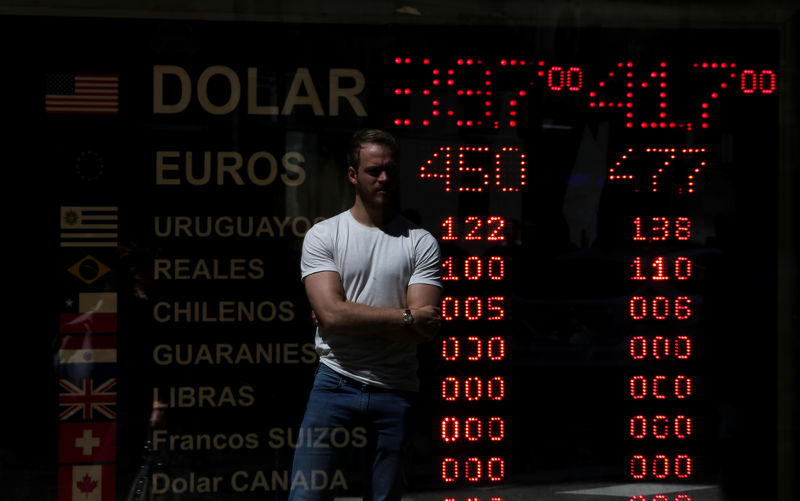 © Reuters. A man is reflected in an electronic board showing currency exchange rates in Buenos Aires' financial district