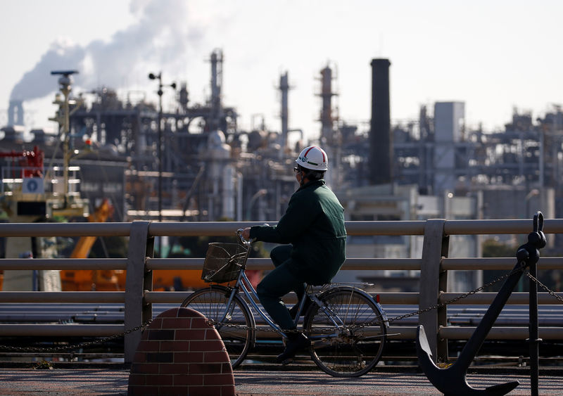 © Reuters. FILE PHOTO:  A worker cycles near a factory at the Keihin industrial zone in Kawasaki