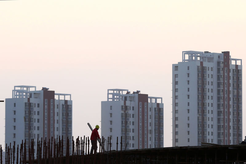 © Reuters. FILE PHOTO: Worker stands on the scaffolding at a construction site against a backdrop of residential buildings in Huaian